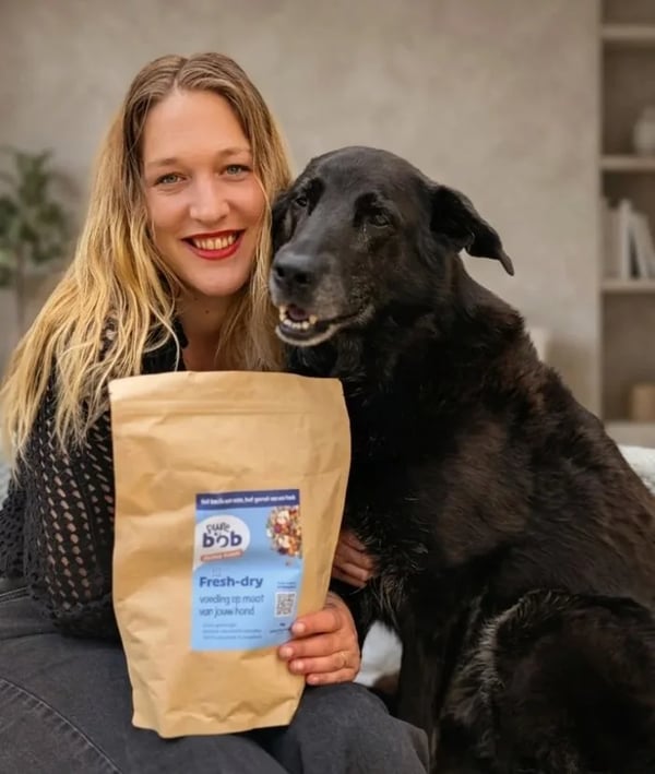 Baasje knuffelt haar zwarte hond met een zak Pure Bob fresh-dry